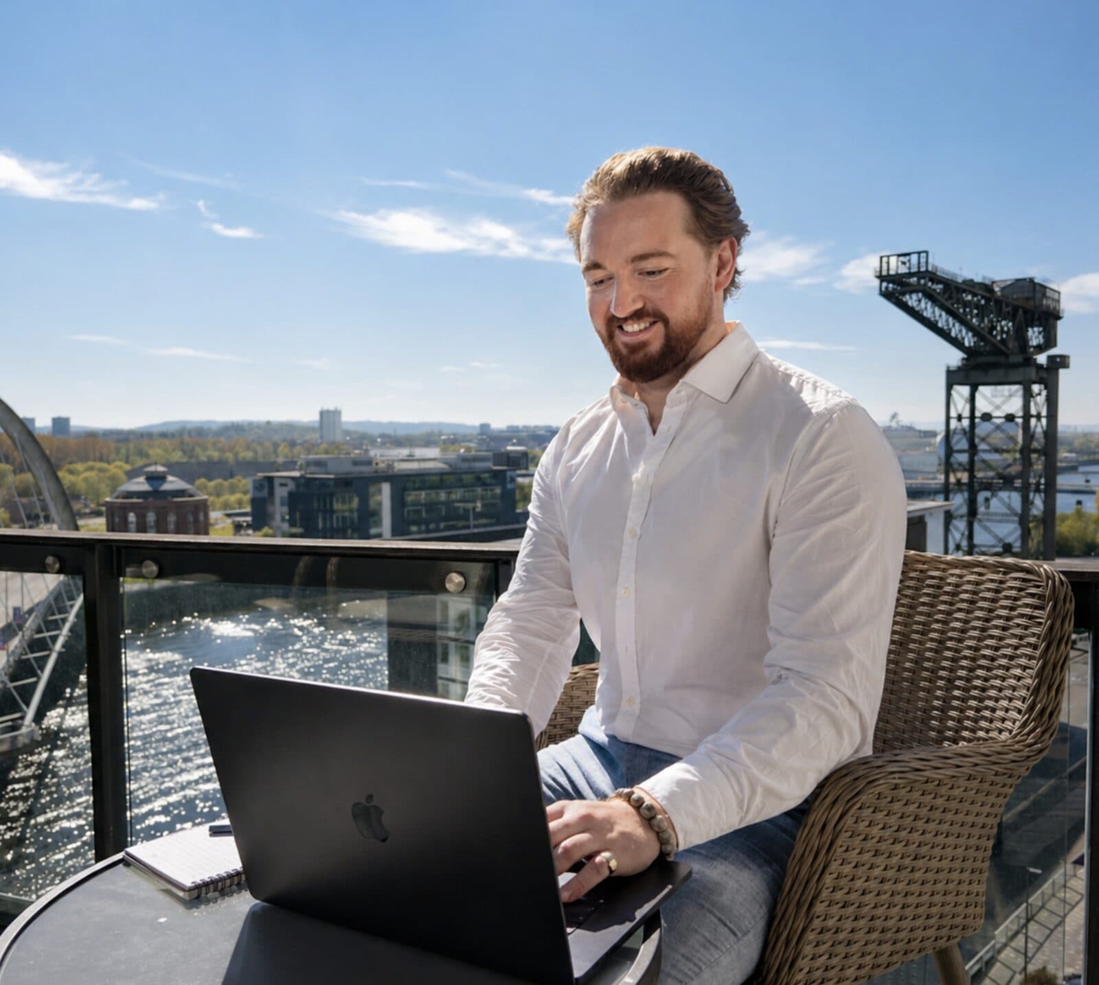 Dr Peter McCann Strain working at a laptop on a sunny Glasgow balcony